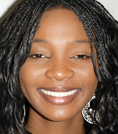 Woman smiling at camera, wearing silver hoop earrings, professional headshot photo.