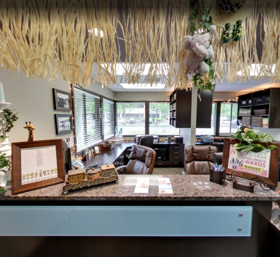 Orthodontic office reception area with waiting seating, plants, and decorative display counter.
