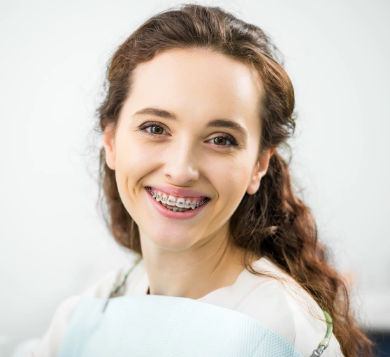 Young woman smiling at camera wearing light blue shirt, professional headshot against white background.
