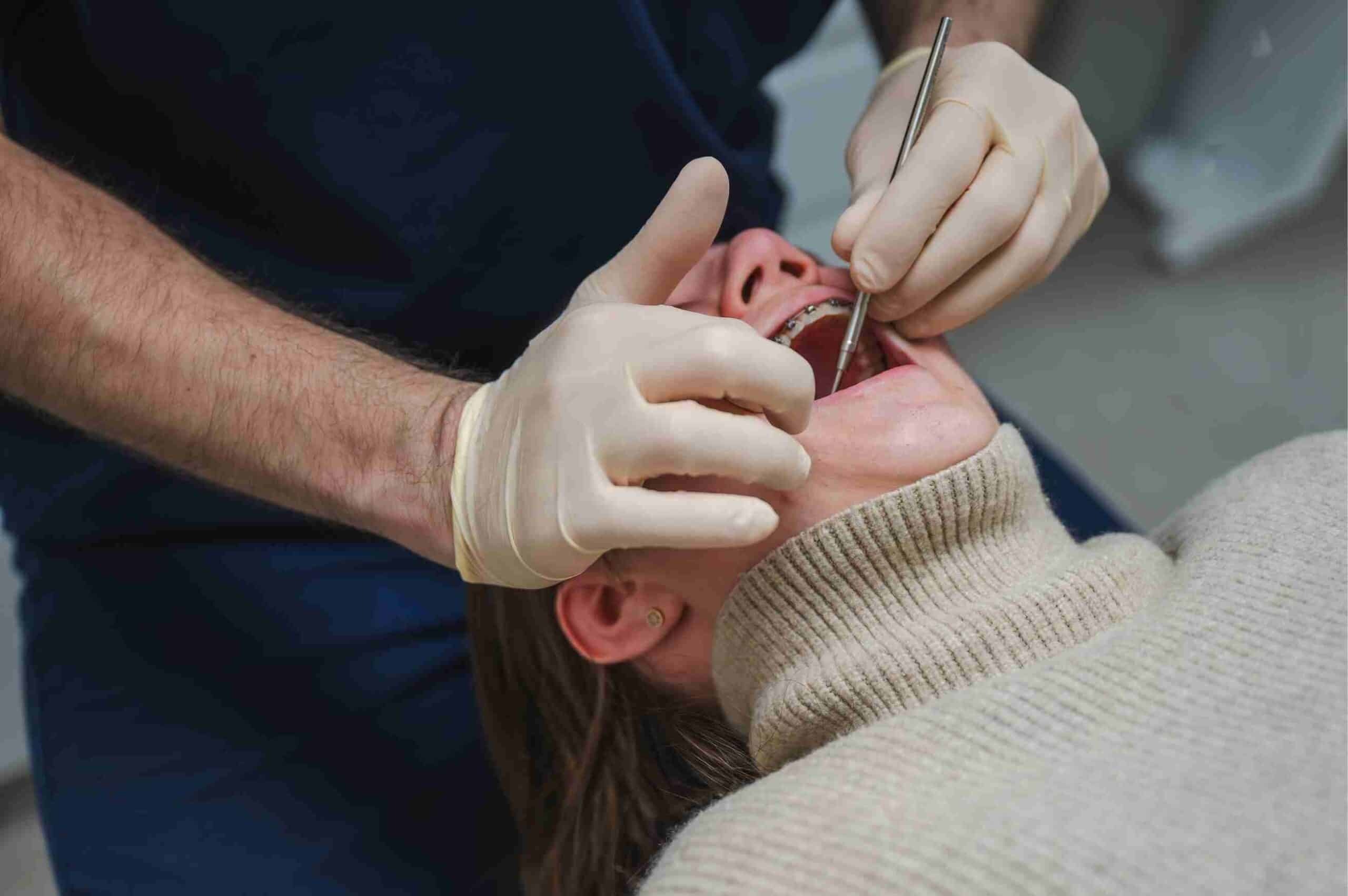 Orthodontist examining infant's mouth during first dental visit with gloved hands.