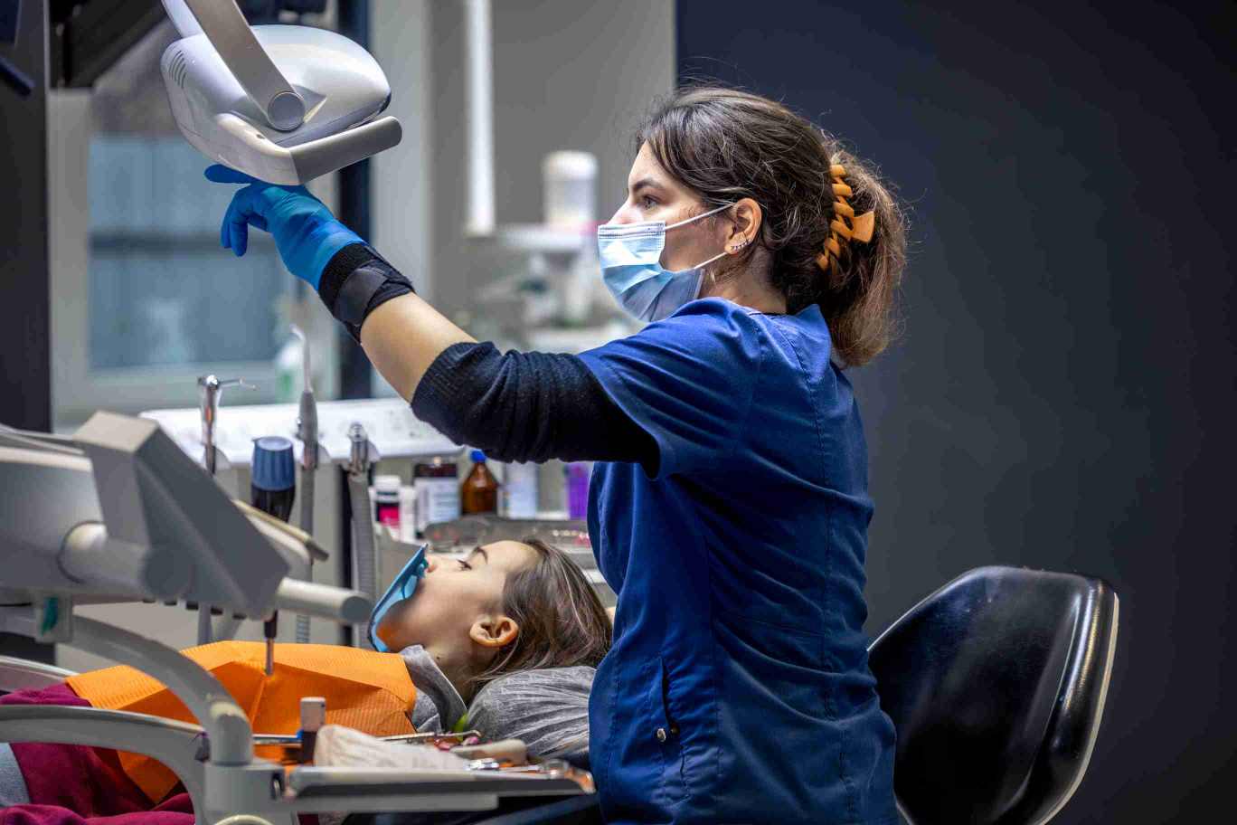 Orthodontist examining child’s teeth for early warning signs of problems.